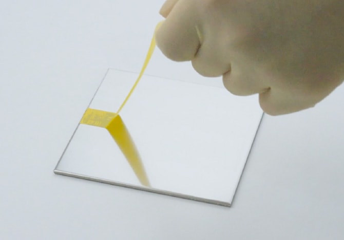 非粘着コーティングされたステンレス板から、粘着テープを剥がしている様子