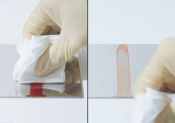 非粘着コーティングされていないステンレス板でのフォトレジスト拭き取りテスト。クリーンワイプで拭っても汚れが伸びて付着し続け、完全には除去できずに赤い跡が残っている様子。